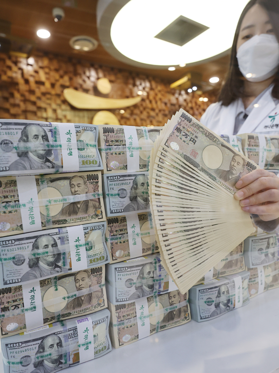 A Hana Bank employee fans out Japanese yen among a stack of U.S. dollars and the Japanese currency at the bank’s headquarters in Myeong-dong in central Seoul on Wednesday. The Japanese yen continued to weaken against the U.S. greenback amid the country reporting its biggest trade deficit in seven years in 2021: a deficit of 5.37 trillion yen ($42.4 billion). The weakening value of the Japanese currency is raising concerns among Korean exporters as Korean products could lose its competitive price advantage when competing with similar Japanese products overseas such as automobiles and steel. [YONHAP] 