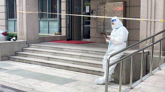 A quarantine personnel stands in front of an apartment building where a person tested positive for Covid-19 lives, in Changning District, Shanghai, which has been under lockdown since March 28. [YONHAP]