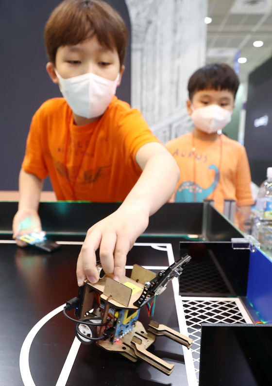 A young participant operates a coding robot during the Education Korea exhibition held at Coex in Gangnam, southern Seoul, on Tuesday. The biggest education exhibition in the country, held for two days, is particularly focused on IT technologies including robotics and artificial intelligence-operated home schooling. Major companies including LG Electronics and KT are participating in the exhibition. [YONHAP] 