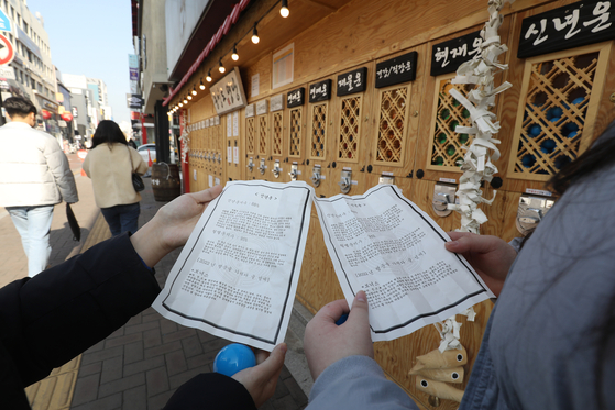 People look at papers detailing their fortune for the year on Jan. 2 in Daegu. [NEWS1] 