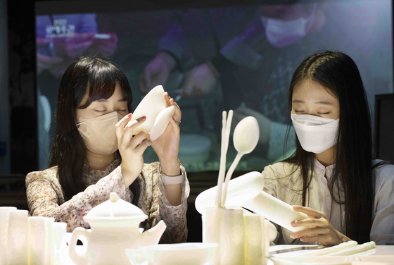 Models close their eyes and feel crafts made by people with limited vision at Korea Craft Week 2022's "Touch in the Dark" exhibition. [KOREA CRAFT & DESIGN FOUNDATION]