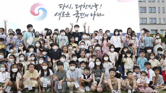 President Yoon Suk-yeol takes a photo with children invited to a housewarming event celebrating the presidential office’s move to Yongsan District in central Seoul Sunday. [JOINT PRESS CORPS]