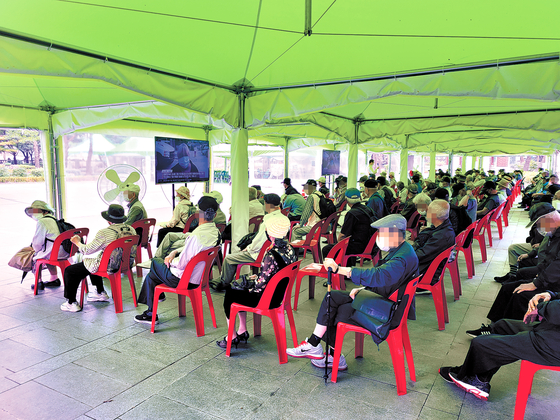 People wait for free meals at a cafeteria in Wongaksa Temple in Jongno District, central Seoul, on Friday. [SUK GYEONG-MIN]