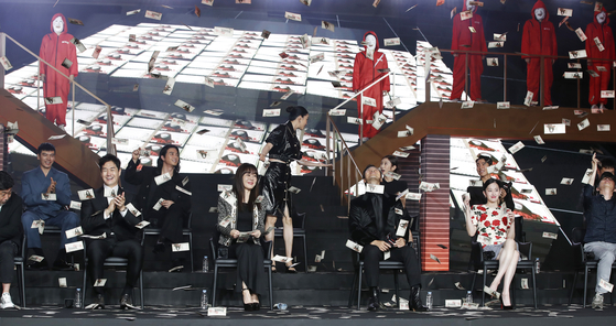 The cast of “Money Heist: Korea – Joint Economic Area” grab bills falling from the money shower at the press event hosted by Netflix Korea at Coex in southern Seoul on Wednesday. [NEWS1]