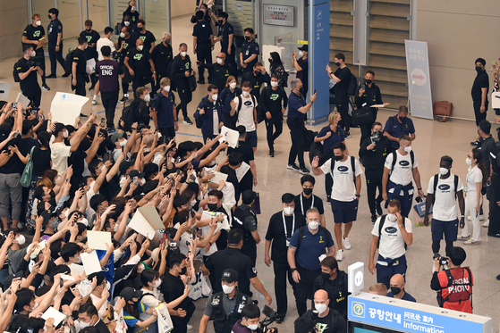 Head coach Antonio Conte, pictured bottom right, leads the Tottenham Hotspur squad and support staff past fans in the Incheon International Airport Arrivals Hall in Incheon on Sunday. The team, which will play two exhibition games in Korea over the next week, were greeted at the airport by Korean forward Son Heung-min, pictured top left, who was already in Korea for international fixtures and the summer break. [YONHAP]