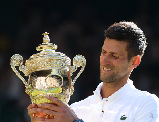 Novak Djokovic celebrates with the trophy after winning the men's singles final against Nick Kyrgios of Australia on Centre Court at the All England Lawn Tennis and Croquet Club in London on Sunday. [XINHUA/YONHAP]