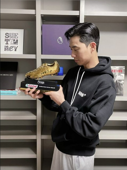 Actor Park Seo-joon, known to be a close friend of Son, holds the Golden Boot trophy while wearing a NOS7 black hoodie at Son’s house. [SCREEN CAPTURE]
