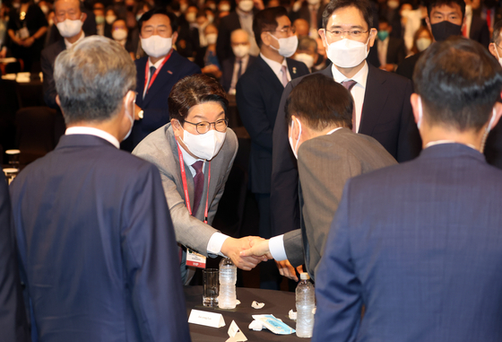 President Yoon Suk-yeol, right, shakes hands with Kweon Seong-dong, the floor leader and acting chief of the People Power Party, at a forum at the Shilla Hotel in central Seoul Wednesday. [YONHAP]