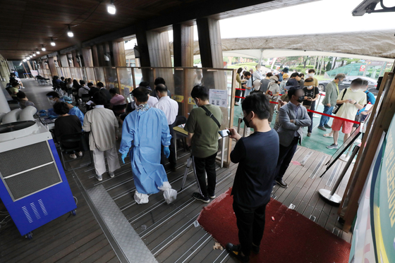 People wait in line to get tested at a testing center in Songpa District, southern Seoul, on Monday. [NEWS1]