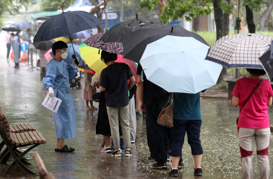 A line of people wait in the rain to be tested for the coronavirus in Daegu on Monday. [NEWS1]