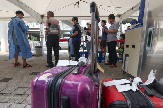 People wait in line at a Covid-19 testing site in Mapo District, western Seoul, on Thursday, some after returning from overseas. [YONHAP]