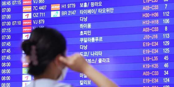 A traveler checks flight schedules on an electric board at Incheon International Airport Terminal 1 on Thursday. [YONHAP]