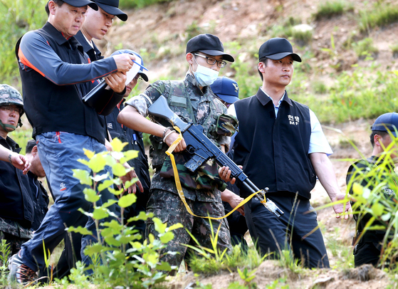 Lim Do-bin, an army sergeant who killed five soldiers and wounded seven others in a shooting spree, reenacts his actions with police in 2014. [JOINT PRESS CORPS]