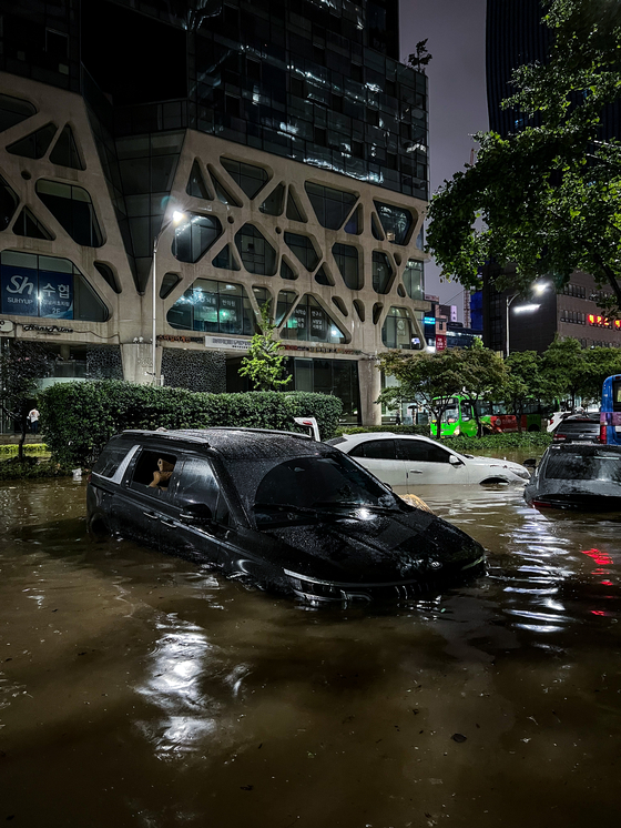 Submerged cars are left abandoned near Gangnam Station Monday evening. [MICHAEL LEE]