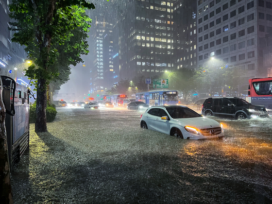 Roads near Gangnam Station are flooded as heavy rain fell Monday evening. [MICHAEL LEE]
