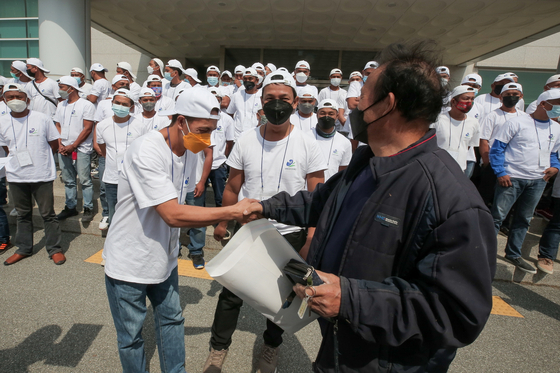 A seasonal worker from the Philippines shakes hands with a Korean farmer last April after arriving in Yanggu County, Gangwon, for temporary work. [YANGGU COUNTY OFFICE]