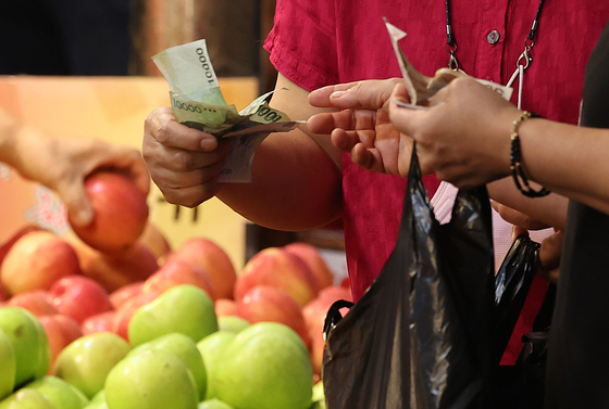 A customer buys apples at the Cheongryangni Fruit & Vegetable Market in Dongdaemun District, eastern Seoul, on Thursday. [YONHAP]