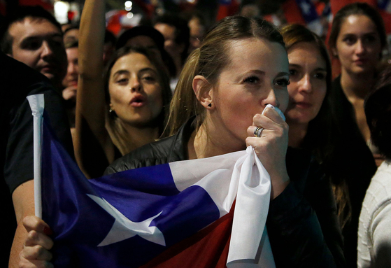 A woman kisses a Chilean flag while people rejecting the new constitution draft celebrate after knowing the first results of the referendum vote, in Santiago, on Sept. 4. A resounding majority in Chile rejected the proposed constitution that sought to change the one inherited from the Augusto Pinochet's dictatorship (1973-1989) for one with more social rights. With almost 100 percent of votes counted, the reject camp led with nearly 62 percent compared to just 38 percent for those in favor. [AFP/YONHAP]