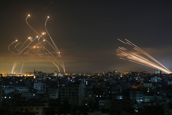 The Israeli Iron Dome missile defence system, left, intercepts rockets, right, fired by the Hamas movement towards southern Israel from Beit Lahia in the northern Gaza Strip as seen in the sky above the Gaza Strip overnight on May 14, 2021. [AFP/YONHAP] 