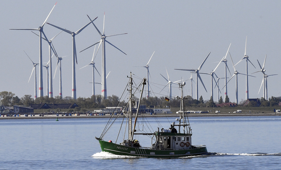 A fisher boat passes wind turbines between the island Langeoog and Bensersiel at the North Sea coast in Germany, in this file photo dated May 15, 2019. Four European Union countries plan to build North Sea wind farms capable of producing at least 150 gigawatts of energy by 2050 to help cut carbon emissions that cause climate change, Danish media reported in May. [AP/YONHAP]