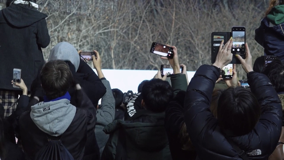 A scene from the film "Fanatic" where fans are filming with their phones hoping to catch sight of their favorite celebrities. [AUD]