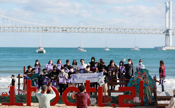 BTS fans gather at Gwangalli Beach in Busan on Thursday before joining a plogging program, which combines jogging and picking up trash. Fans have descended on the coastal city to celebrate BTS member Jimin’s birthday and the boy band’s concert on Saturday, which has been organized to promote Busan’s bid to host World Expo 2030. [YONHAP] 