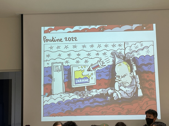 Plantu showing one of his works during a talk with local students and cartoonists at the headquarters of Jipyong Brewery in Seoul on Oct. 30. [ESTHER CHUNG]