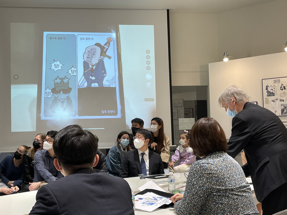 Plantu showing a satirical cartoon by a Korean cartoonist during a talk with local students and cartoonists at the headquarters of Jipyong Brewery in Seoul on Oct. 30. [ESTHER CHUNG]