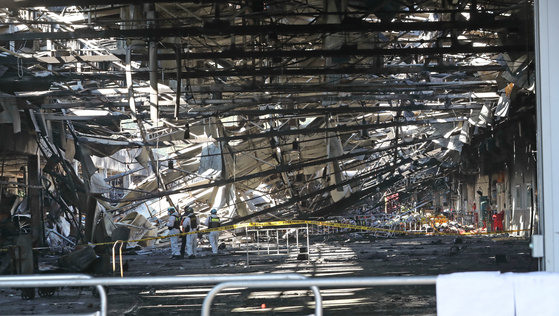 Police and firefighters hold a joint investigation on Wednesday morning after the blaze was extinguished. [YONHAP]
