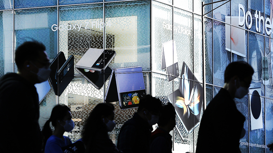 Passengers pass by a Samsung Electronics retail shop in Seoul. [NEWS1]