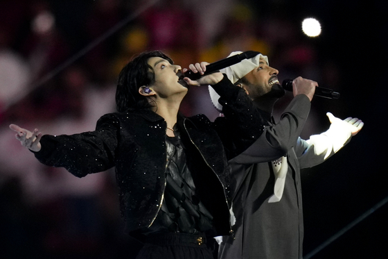 BTS member Jungkook, left, performs with Qatari singer Fahad Al Kubaisi during the opening ceremony of the 2022 Qatar World Cup at Al-Bayt Stadium in Al Khor, Qatar on Sunday.  [AP/YONHAP]