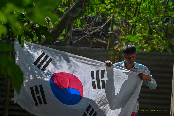 Bangladeshi chemist Abu Kowsir puts up a flag in Bancharampur, Bangladesh on Nov. 16.  [AFP/YONHAP]