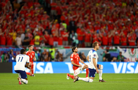 England's Harry Kane takes a knee alongside his teammates and Wales players before the match between Wales and England at the 2022 FIFA World Cup at Ahmad Bin Ali Stadium in Al Rayyan, Qatar on Tuesday. [REUTERS/YONHAP] 