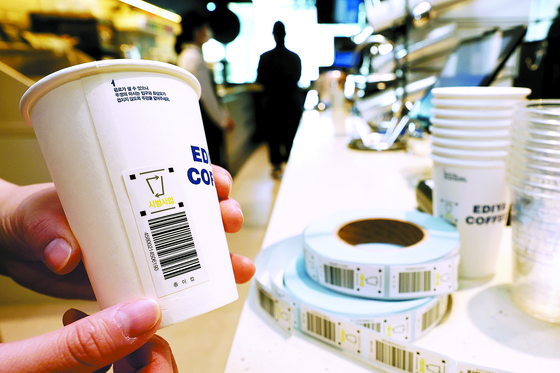 A bar code is attached to a disposable cup for take-out. A deposit-return system for disposable cups will begin in the city of Sejong and Jeju Island starting Friday. [JANG JIN-YOUNG]