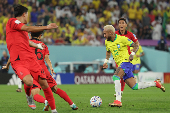 Neymar, right, dribbles the ball against the Korean defense on Monday during a round of 16 match between Korea and Brazil at Stadium 974 in Doha, Qatar. [NEWS1]