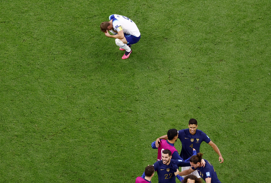 England's Harry Kane reacts after the match on Saturday when England were eliminated from the World Cup while France's Raphael Varane celebrates with teammates as France progressed to the semi finals. [REUTERS/YONHAP]