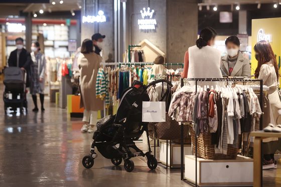 Parents with infants under the age of 2 will be receiving a higher monthly payment from the government starting next year, according to the Ministry of Health and Welfare Tuesday. Households with a baby under the age of 1 will receive 700,000 won ($535) a month, and 350,000 won will be disbursed to those with a child younger than 2 but not younger than 1. Above shows people shopping clothing for kids at a shopping mall in Seoul on Tuesday. [YONHAP]