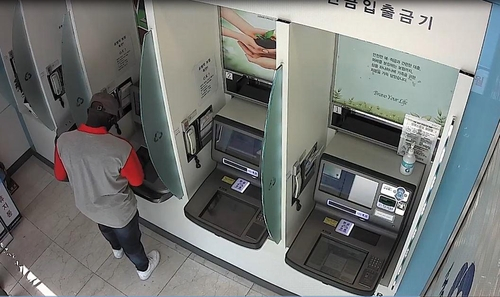 Above shows a suspect withdrawing money after defrauding victims in romance schemes, in a photo provided by the Seoul Metropolitan Police Agency, on Dec. 15. [YONHAP] 