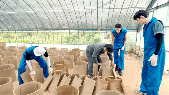 Yoo Jae-suk, Kim Yeon-koung and Lee Kwang-soo make traditional Korean tiles in "Korea No. 1." [NETFLIX]