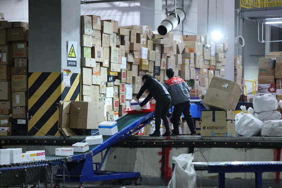Workers process parcels for door-to-door delivery services at a logistics center in Seoul on Tuesday ahead of the Lunar New Year holiday, which runs from Jan. 21 to 24. Known as Seollal in Korea, the Lunar New Year holiday is one of the two major Korean traditional holidays, during which many Koreans exchange gifts. [YONHAP] 