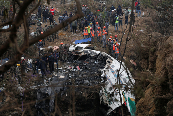 A rescue team works to recover the body of a victim from the site of the plane crash of a Yeti Airlines operated aircraft, in Pokhara, Nepal on Monday. [REUTERS/YONHAP]