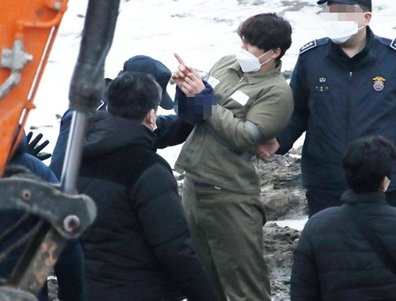 Lee Ki-young points to where he allegedly buried the body of his former girlfriend at a stream in Paju, Gyeonggi, on Jan. 6. [YONHAP] 