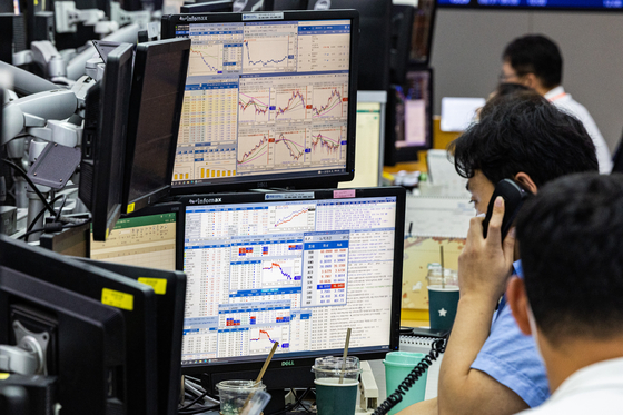 Employees at Hana Bank in central Seoul process transactions in a dealing room in August. [YONHAP]