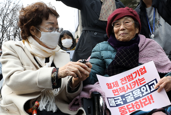 Lee Yong-soo, left, a survivor of the Japanese military’s wartime sexual slavery, and Yang Geum-deok, a forced labor victim, hold hands at a rally marking the 104th anniversary of the March 1 Independence Movement and demand an apology from Japan at Seoul Plaza in downtown Seoul on Wednesday. On this day, various liberal and conservative groups held large-scale rallies to mark the anniversary. [NEWS1]
