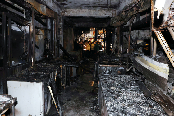 Officials examine the charred ruins of the Hyeondae Market in Dong District, Incheon, on Sunday morning after a massive overnight fire burned down 55 of the market's 212 stores. [YONHAP]