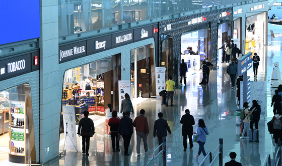 Travelers pass by the duty-free shops at Incheon International Airport Terminal 2 on March 2. Lotte Hotel, Hotel Shilla, Shinsegae and Hyundai Department Store Duty Free and China Duty Free Group have submitted license bids for space at the airport. Designated operators will open on July 1. [YONHAP] 