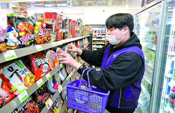 Song Yoo-seok, 27, the manager of CU's Junghwa Station branch in eastern Seoul, arranges products on to the stalls on March 7. [KANG JEONG-HYEON]