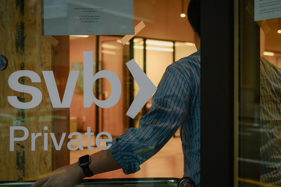 An employee holds the door open at the Silicon Valley Bank branch office in downtown San Francisco, California, on Monday. [REUTERS]