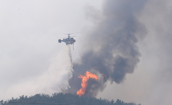 A helicopter on Monday continues to extinguish a fire that broke out in Hongseong County, South Chungcheong, on Sunday. [YONHAP] 