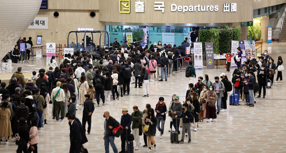 Passengers form a queue in the departure hall of Gimpo International Airport on March 19. [NEWS1]